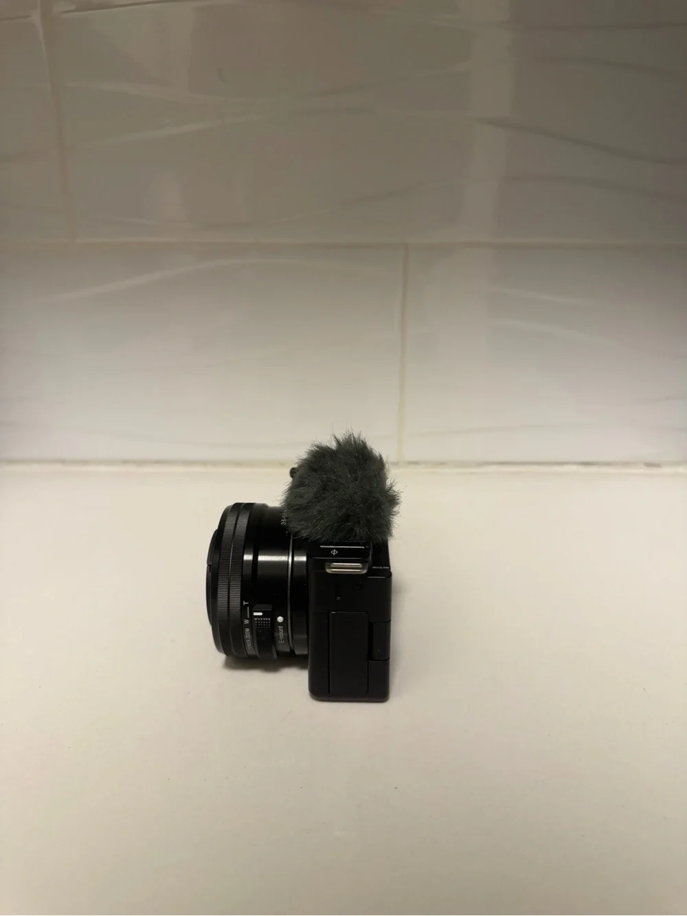 Sony Black Mirrorless Camera with Lens and Gray Wind Muff
